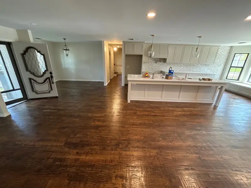 Dark hand-scraped hardwood floor through an open kitchen and entry